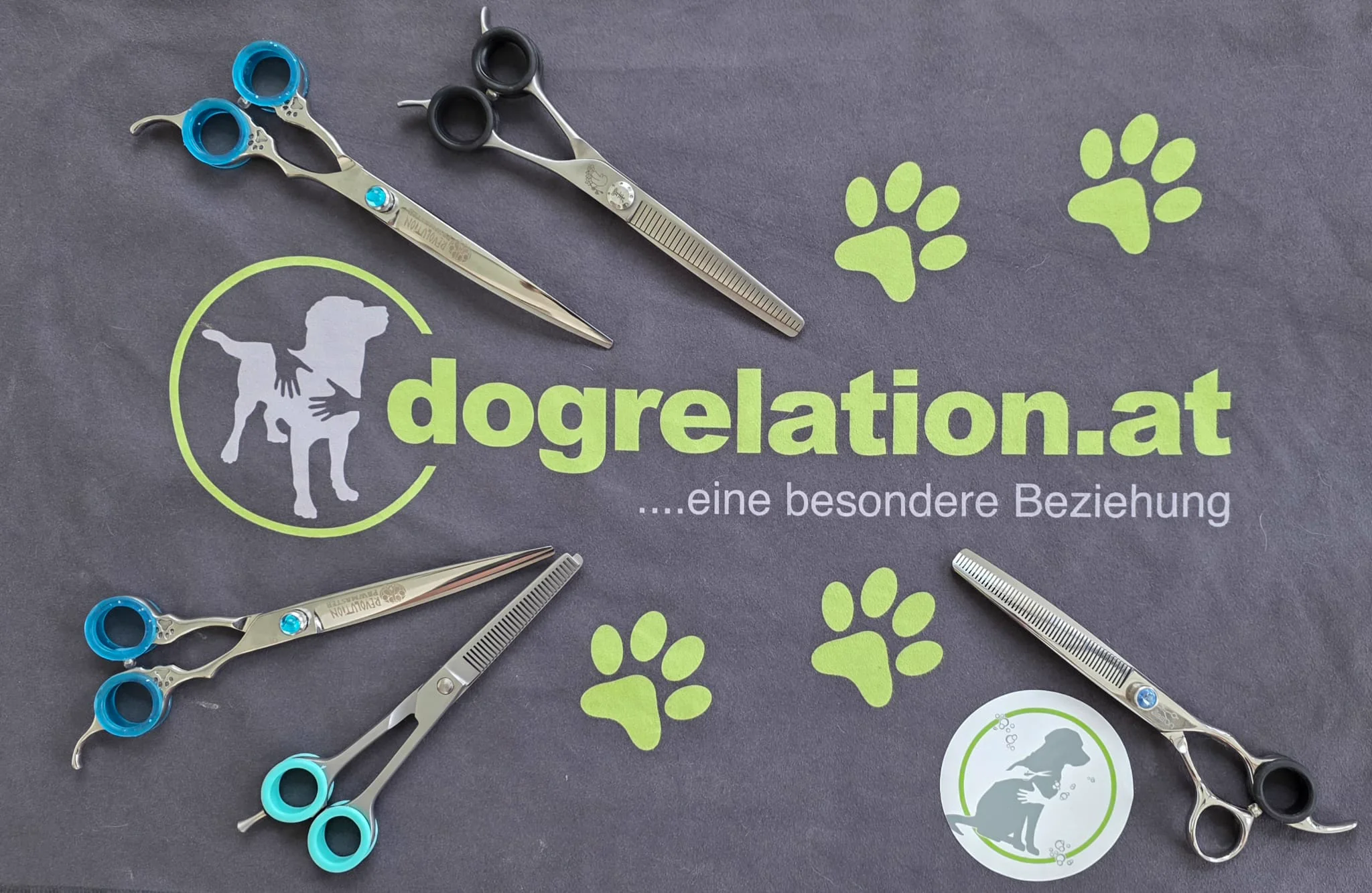 Hundefriseur-Werkzeuge mit Scheren und Pfotenabdrücken auf dem Dogrelation-Logo – Hundesalon Enns